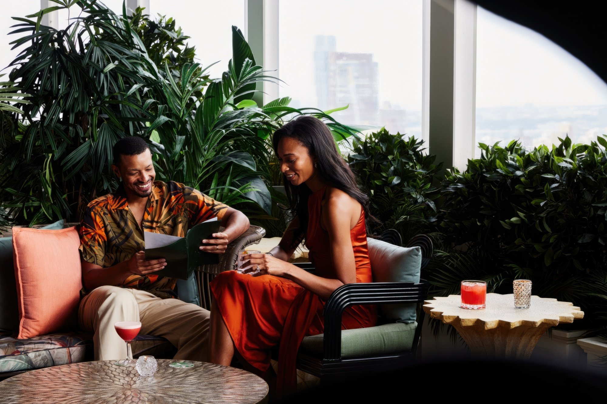 A couple drinks cocktails while perusing a restaurant menu.