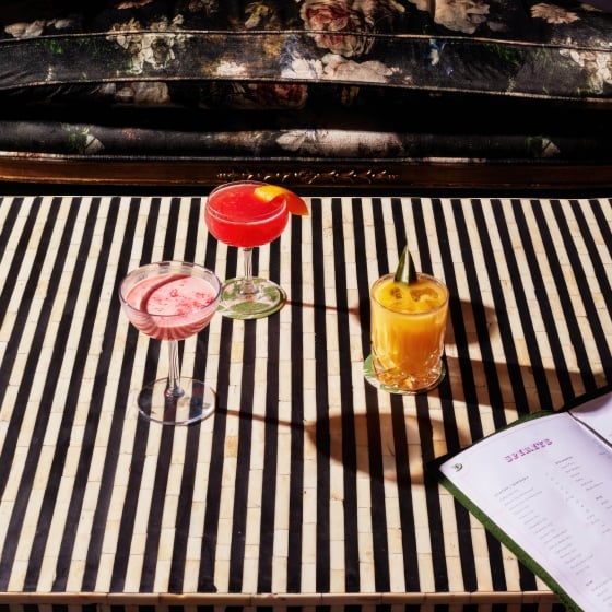 Three assorted cocktails on a black and white striped table.