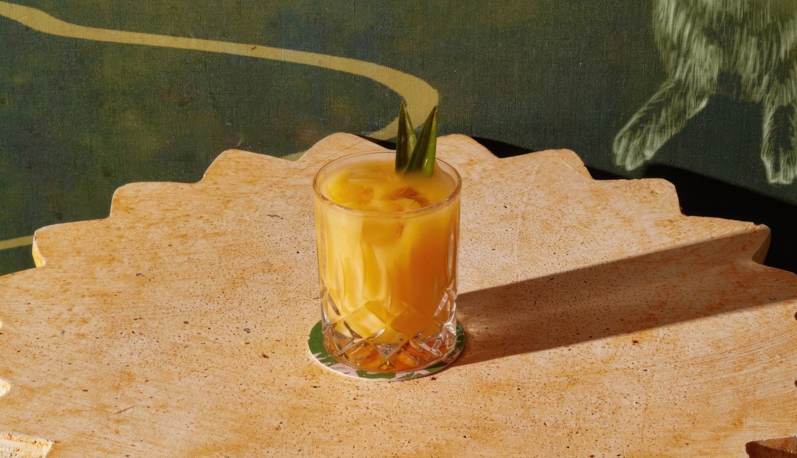 A yellow cocktail on a stone table.