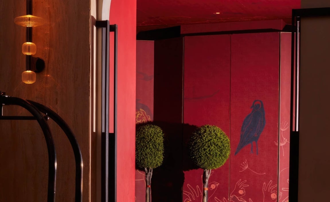 A lounge area with red walls and ceiling and blue velvet couch.