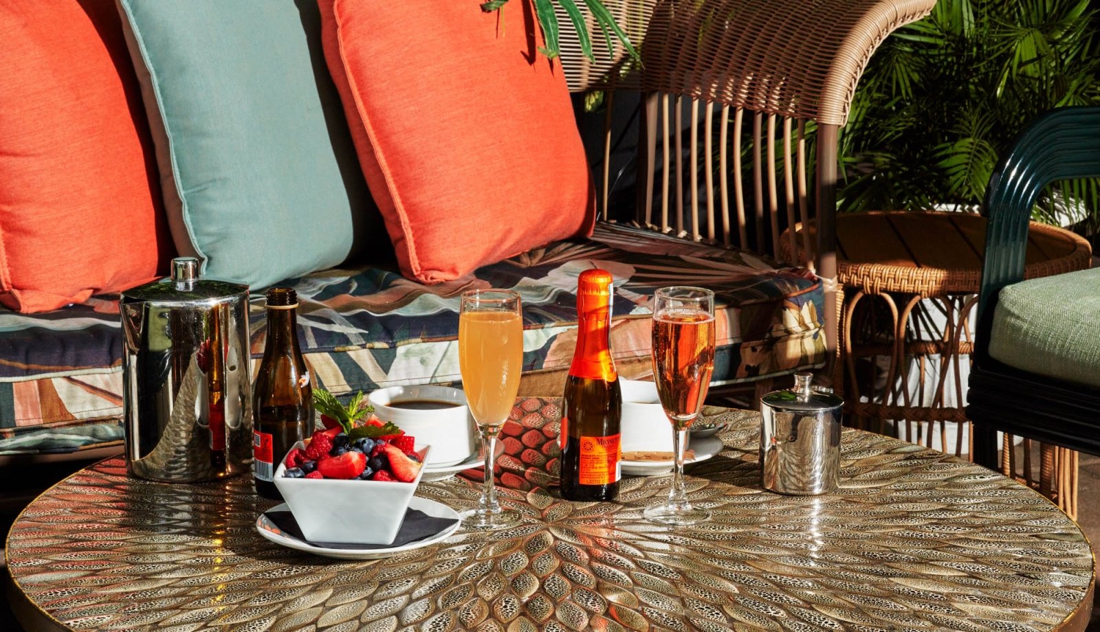 An assortment of drinks and fruit on a warm patio terrace.