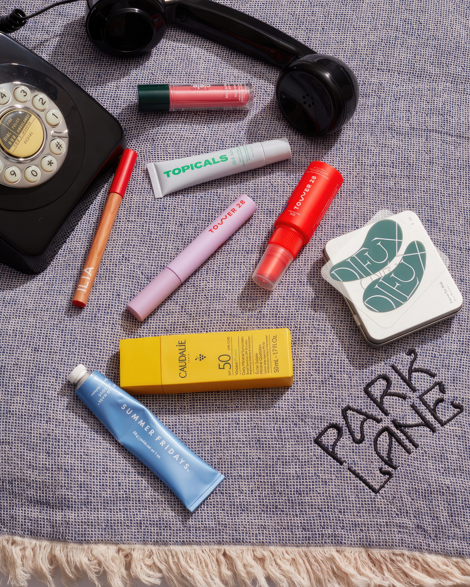 An assortment of beauty products laid out of a blanket embossed with 'Park Lane'.