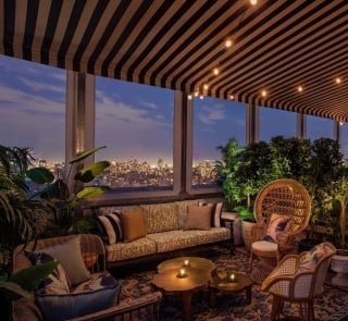 A cozy lounge area with warm lighting at dusk, New York City skyline in the background.