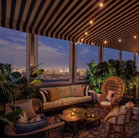 A cozy lounge area with warm lighting at dusk, New York City skyline in the background.