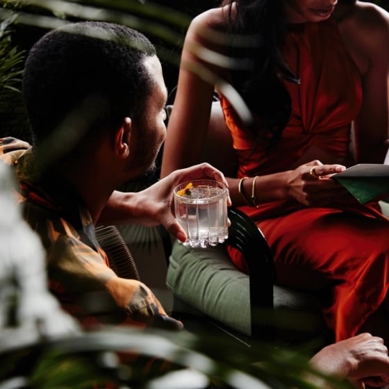 A couple reading a restaurant menu while drinking cocktails.