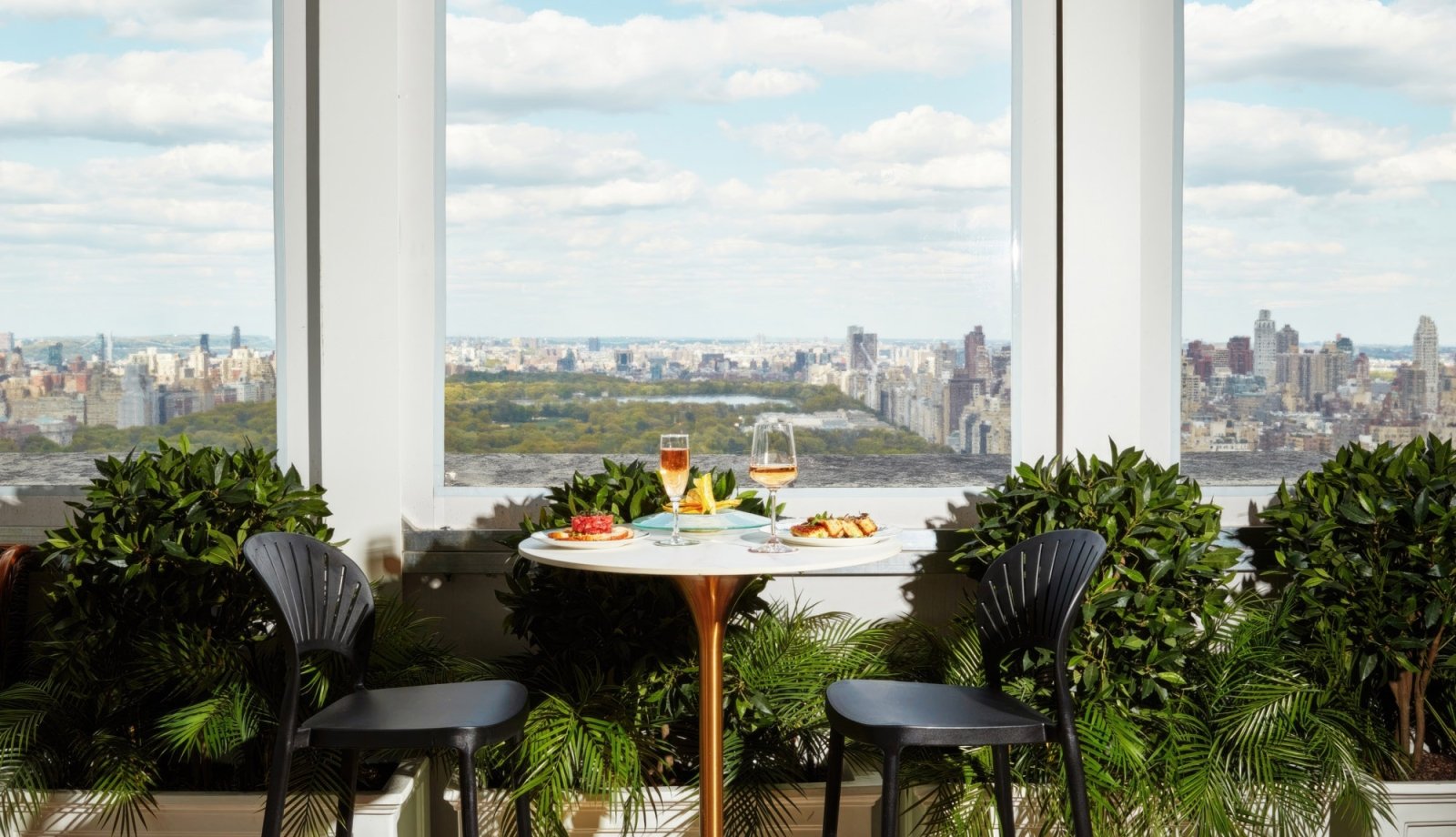 A two-seater table with breakfast by a window overlooking Central Park.