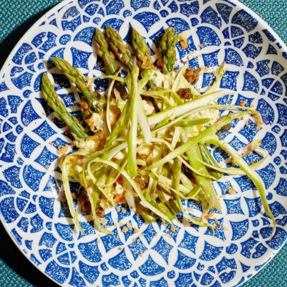 A shredded asparagus salad on a blue and white plate.