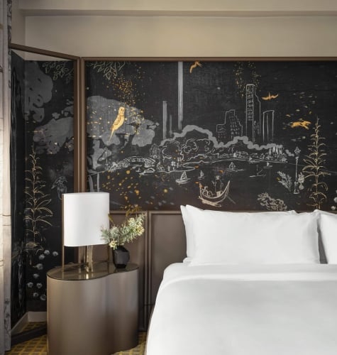 A king bed with painted mural behind it in a suite at Park Lane New York.