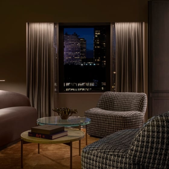 A seating area with two checkered chairs, brown leather sofa and tiered table in the Belvedere Suite at Park Lane New York.