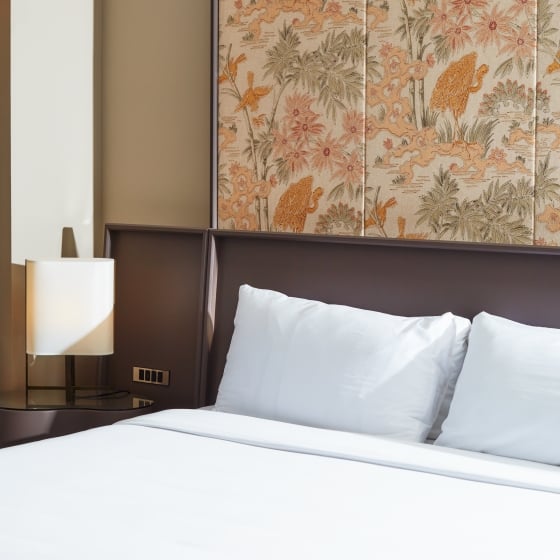 A king bed and side table with a painted mural behind.