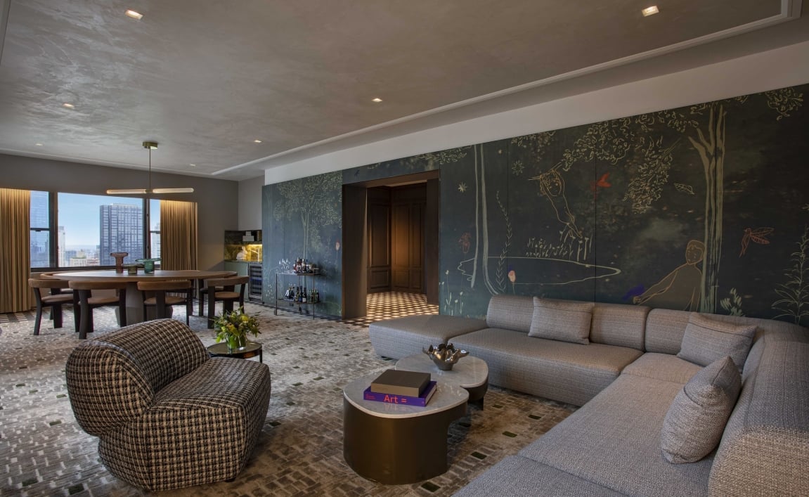 A large living area with sectional couch, dining area and walls with hand painted murals at Park Lane New York.