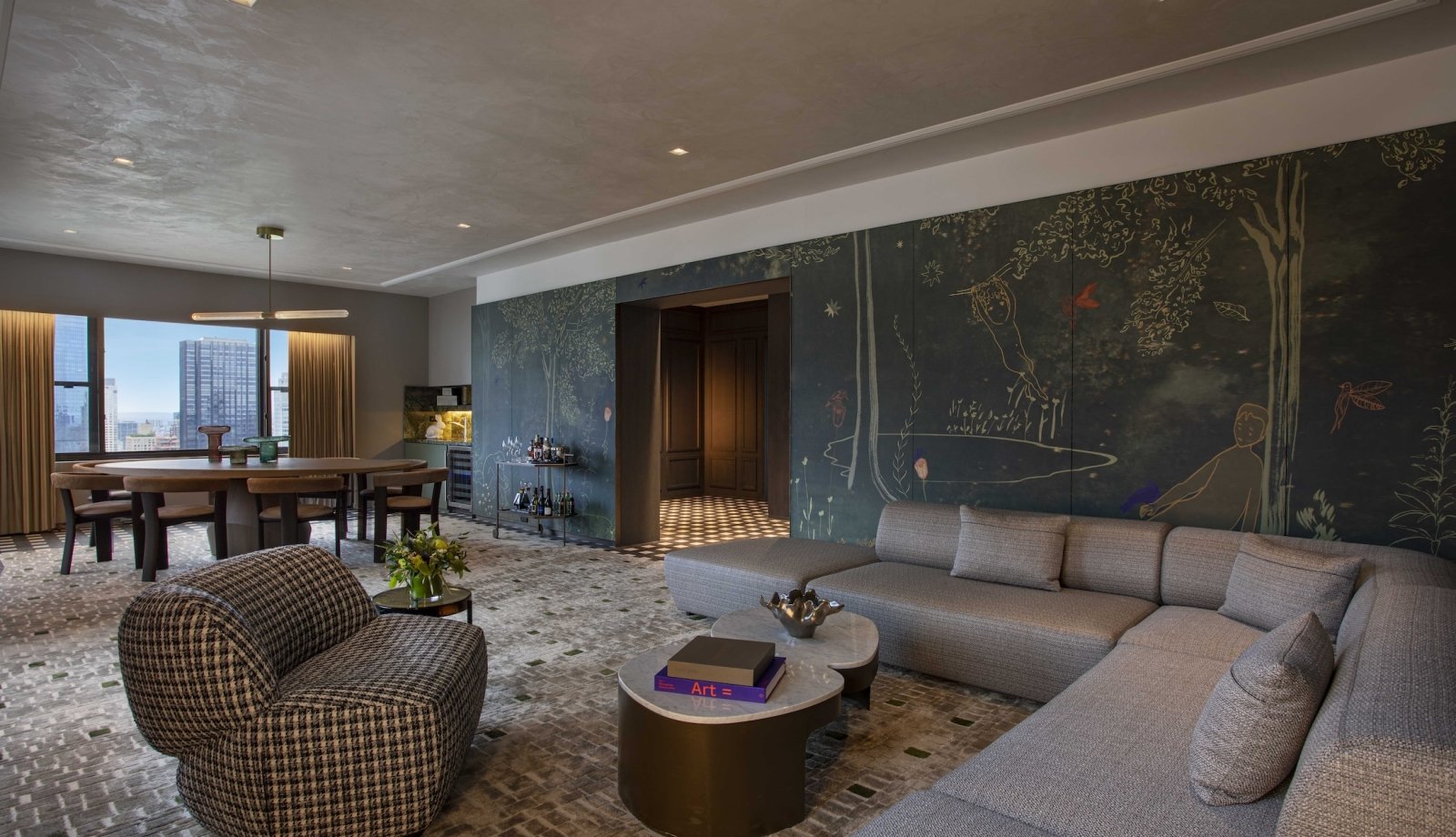 A large living area with sectional couch, dining area and walls with hand painted murals at Park Lane New York.