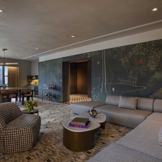 A large living area with sectional couch, dining area and walls with hand painted murals at Park Lane New York.