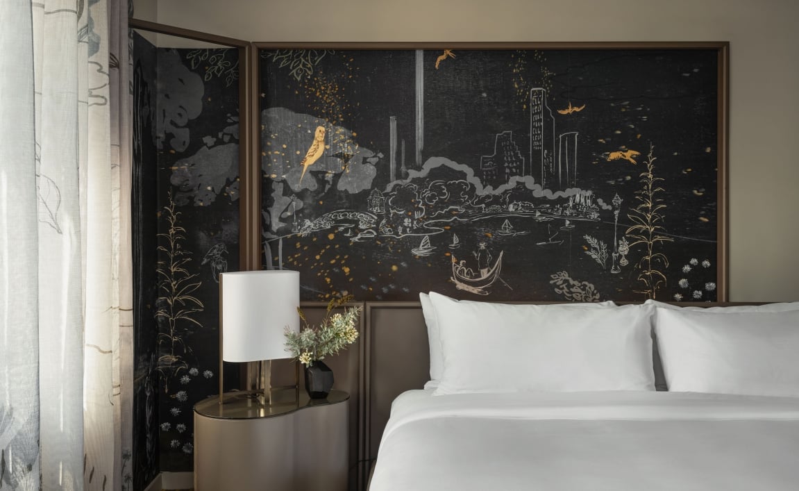 A king bed and night table with a hand painted mural behind.