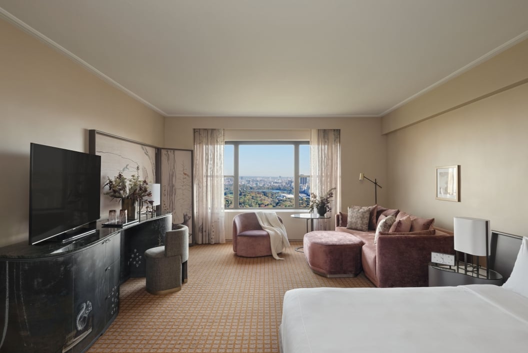 The seating area and king bed of a suite at Park Lane New York with view of Central Park.