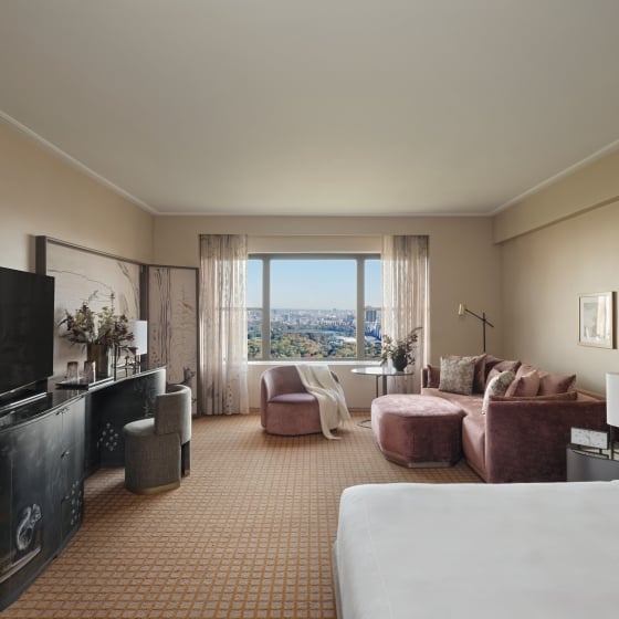 The seating area and king bed of a suite at Park Lane New York with view of Central Park.