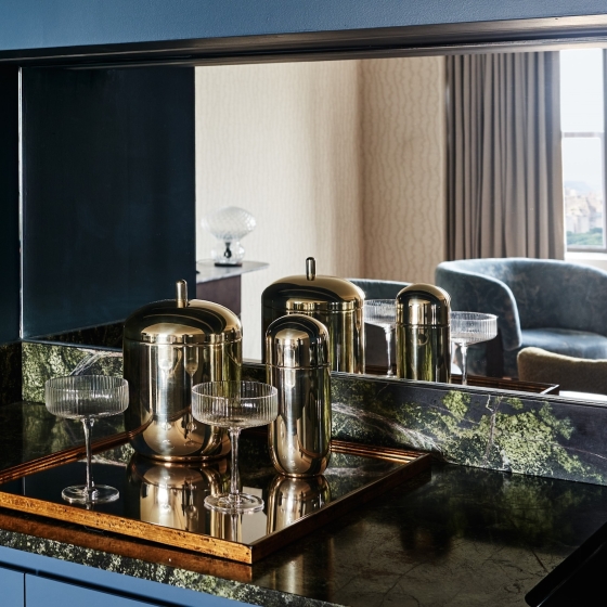 An elegant bar with delicate glasses and gold tumblers in a suite at Park Lane New York.