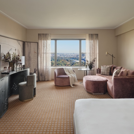 A king bed and seating area including couch, chair and desk in a studio suite overlooking Central Park at Park Lane New York.