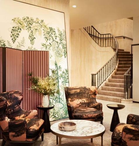 The seating area of a lobby with a staircase in the background.